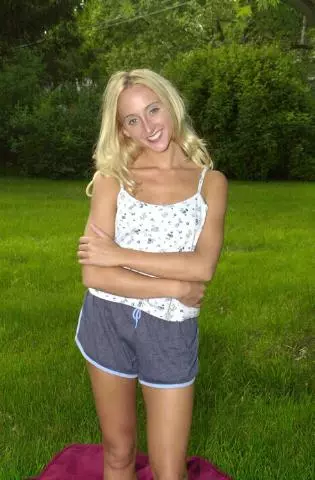 blonde Ukrainerin in Shorts und Top steht auf einer Wiese